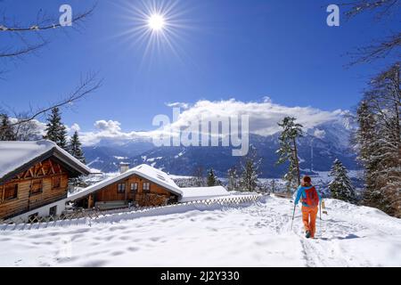 Mujer senderismo camina sobre la nieve cuesta cubierta hacia el restaurante San Martín, Kramerplatauweg, Garmisch, Ammergau Alpes, Werdenfelser Land, Alta Baviera, Baviera, Alemania Foto de stock