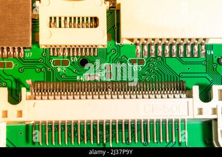 Vista superior de la placa PCB de un lector de tarjetas CF, micro SD y SD. Macro, elementos de circuito electrónico y entradas de conexión en la placa PCB. Conector soldado Foto de stock