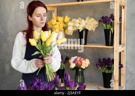 Mujer florista trabaja. Joven dama bonita hace un ramo de tulipanes amarillos. Gran regalo para el día de la madre o el día de San Valentín. Foto de stock