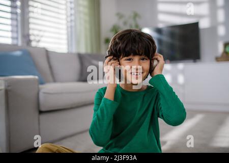 Feliz niño multirracial con auriculares escuchando música en casa. Foto de stock