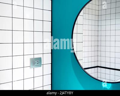 Primer plano azulejos blancos de cerámica con rejilla patrón de pared de baño vista reflejada en una gran forma redonda del espejo sobre fondo de pared azul, estilo mínimo.