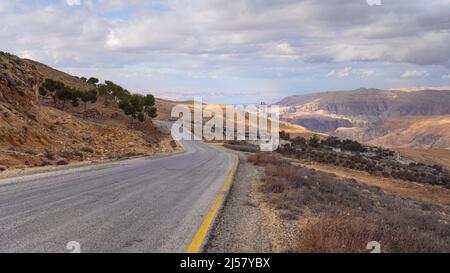 Carretera en terreno montañoso cerca de Tafila, Jordania, Mar Muerto en fondo distante. Foto de stock