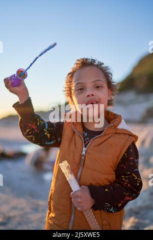 Retrato lindo niño con síndrome de Down jugando con varita de burbujas
