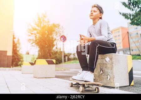 Adolescente patinador niño retrato en una gorra de béisbol con skateboard viejo en la calle de la ciudad. Generación de jóvenes Gasto en tiempo libre y gente activa