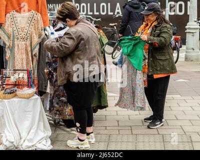 Se ve a dos mujeres revisando ropa de segunda mano en un mercado libre.  Después de dos años de restricciones, las celebraciones del Día del Rey de  este año se normaron. El