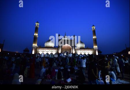 NUEVA DELHI, INDIA - 2 DE MAYO: Los musulmanes se reúnen para su Iftar Roza delante de Jama Masjid iluminado en la víspera del festival Eid-ul-Fitr el 2 de mayo de 2022 en Nueva Delhi, India. La India está destinada a celebrar Eid-al-Fitr el martes, ya que el ayuno del Ramadán se extendió por otro día con la luna creciente no vista el domingo por la noche. En muchas partes del mundo, Eid es uno de los festivales islámicos más importantes que se celebra el lunes. El Masjid-i Jehan Numa, comúnmente conocido como el Jama Masjid de Delhi, es una de las mezquitas más grandes de la India. Fue construido por el emperador mogol Shah Jahan entre 1650 y. Foto de stock