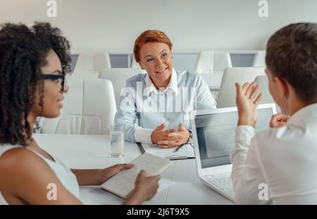 Retrato de una empresaria escuchando a sus empleados sentados delante de ella Foto de stock
