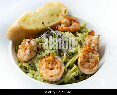 Espaguetis pesto cubierto con gambas y pan de ajo Foto de stock