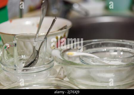 los utensilios de cocina sucios parcialmente cubiertos con detergente sud en proceso de encerar a mano Foto de stock