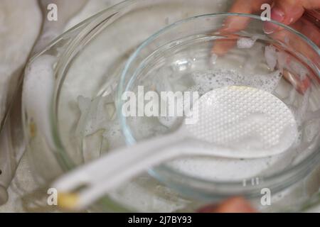 los utensilios de cocina sucios de vidrio parcialmente cubiertos con detergente sud en proceso de encerar a mano Foto de stock