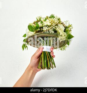 Ramo de boda creado en un marco de ramas verdes en una mano de mujer Foto de stock