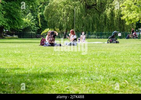 Epsom Surrey, Londres, mayo de 09 2022, Grupos de jóvenes sentados en la hierba en un parque relajante y hablando Foto de stock