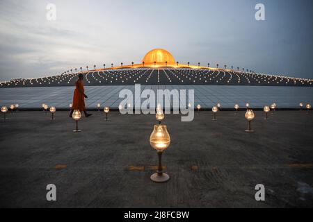 Pathum Thani, Tailandia. 15th de mayo de 2022. Monjes y voluntarios encienden las velas LED con un mando a distancia antes de que el ritual del Día de Vesak comience por la noche. Foto de stock