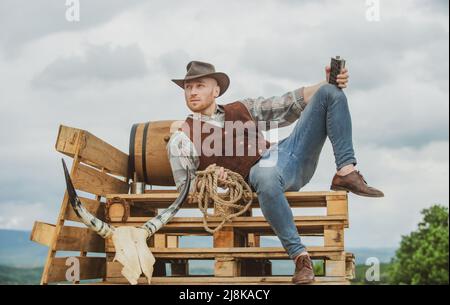 Hombre occidental sexy con sombrero de vaquero hombre atractivo con whisky  o brandy