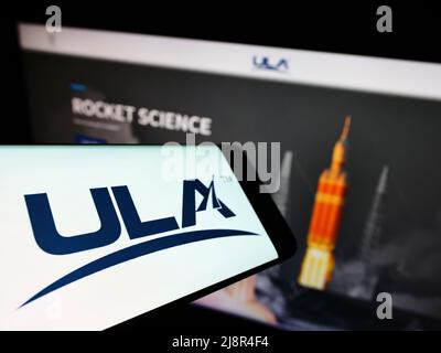 Smartphone con el logotipo de la compañía espacial estadounidense United Launch Alliance (ULA) en la pantalla frente al sitio web. Enfoque en el centro de la pantalla del teléfono. Foto de stock