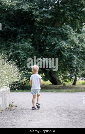 En el verano, un niño se perdió en un parque, él buscando a sus padres. Foto de stock