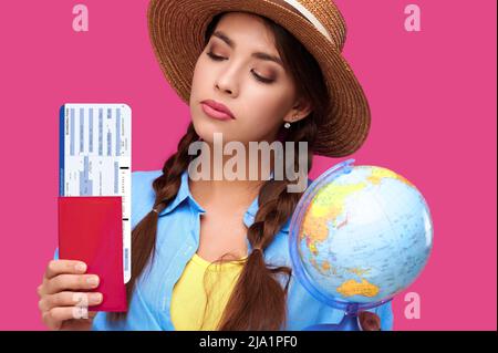 Viajera estudiante con boletos de avión, pasaporte y globo, fondo aislado. Imagen de estudio. Concepto de viaje de vuelo aéreo Foto de stock