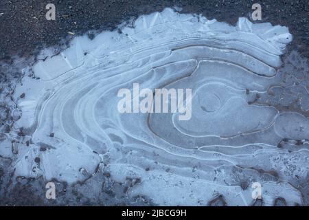 Charco congelado con patrones circulares de hielo Foto de stock