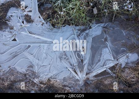 Patrones de hielo abstractos en charcos de agua congelada, vista desde arriba Foto de stock