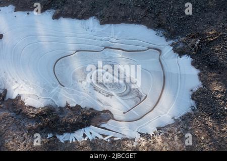 Charco congelado en invierno con patrones circulares de hielo Foto de stock