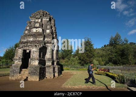 Un hombre caminando lejos del templo de Bima, un templo hindú antiguo en la meseta de Dieng, que se encuentra administrativamente en Dieng Kulon, Batur, Banjarnegara, Java Central, Indonesia. Foto de stock