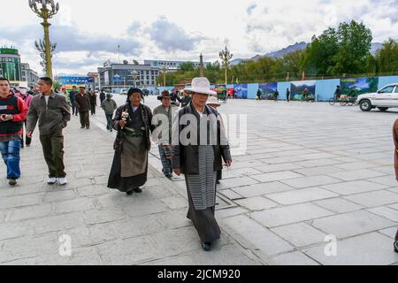Los tibetanos caminan delante del Palacio Potala como parte de su adoración. Foto de stock