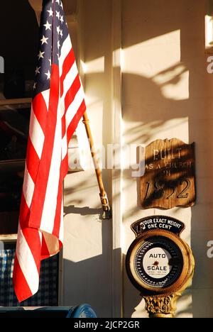 Una bandera estadounidense cuelga fuera de una tienda general histórica que celebra el Día de la Independencia el 4 de julio en un soleado día de verano Foto de stock
