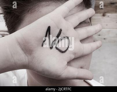 Niño cubriendo su cara con su mano SIN escribir EN ella en marcador Foto de stock