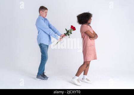 Concepto de la zona del amigo con niño adolescente tratando de besar y dar flores a la niña adolescente y ella lo rechaza Foto de stock