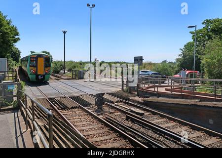 Ford, West Sussex, Reino Unido. Un tren de Southern Network cruza el cruce de nivel mientras los coches esperan en la barrera baja. Foto de stock