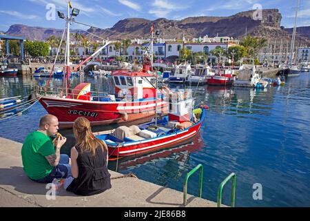 Pareja descansando en barcos de pesca en el puerto de Puerto de Mogan, Gran Canaria, Islas Canarias, España, Europa Foto de stock