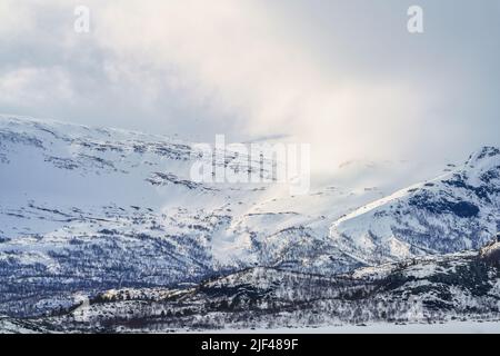 Paisaje invernal con altas montañas con nieve y clima soleado en abril, Stora sjöfallet Parque Nacional, Laponia Sueca, Suecia Foto de stock