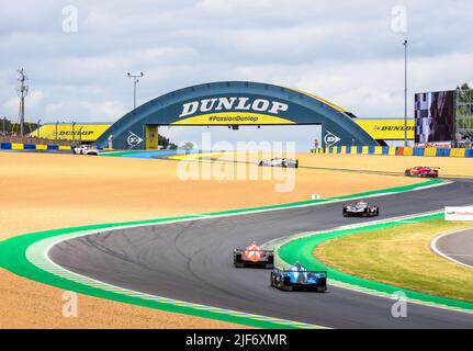 Los coches de carreras manejan la chicane de Dunlop antes de pasar bajo el puente peatonal de Dunlop en el circuito de la Sarthe durante las 24 horas de Le Mans. Foto de stock