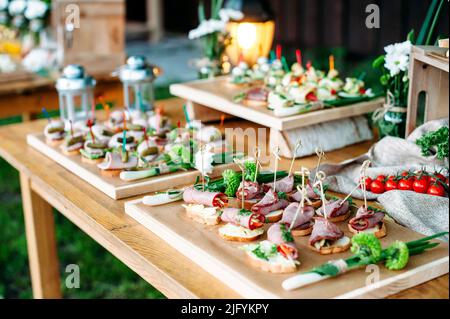 Hermosa mesa de buffet banquetes catering decorada en estilo rústico en el  jardín. Diferentes aperitivos, bocadillos y cócteles. En el exterior  Fotografía de stock - Alamy