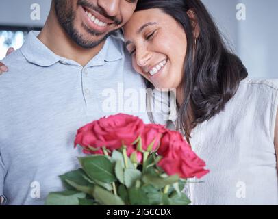 Siempre haciendo los gestos más dulces. Un hombre irreconocible sorprendiendo a su novia con flores en casa. Foto de stock