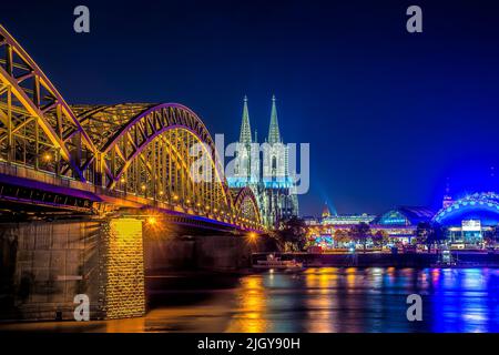 Catedral de Colonia iluminada y Puente Hohenzollern por la noche Foto de stock