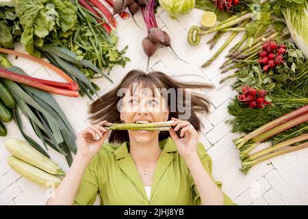 Mujer con ingredientes alimenticios saludables por encima de su cabeza Foto de stock