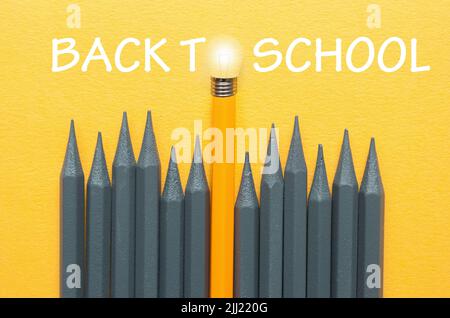 De vuelta a la escuela bombilla de lápiz Destacando entre lápices grises con punta de bombilla, concepto de éxito de ideas únicas Foto de stock