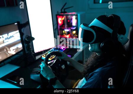 Jugador usando gafas VR usando el volante en casa Foto de stock
