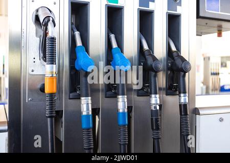 Cinco mangueras de combustible negras y azules en una gasolinera. El ...