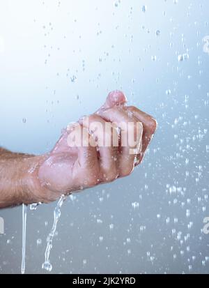 Consiga debajo de esas uñas también. Fotografía de estudio de un hombre irreconocible sosteniendo su mano bajo el agua corriente sobre un fondo gris. Foto de stock
