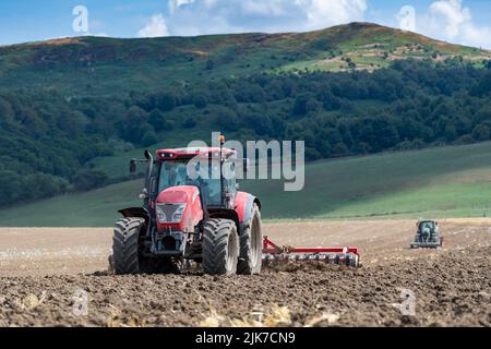 Granjero con un tractor McCormick preparando el lecho de semillas, mientras que un tractor con sembradora de semillas sigue. North Yorkshire, Reino Unido. Foto de stock