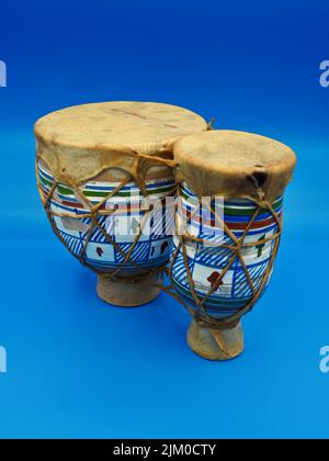 vista aislada de un tambor de bongo africano sobre un fondo azul neutro Foto de stock