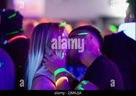 Una pareja besando en una fiesta en un club nocturno Foto de stock