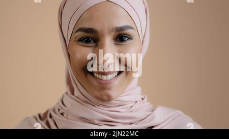 Retrato sonriente mujer musulmana foto de cerca cara niña en hijab mirando la cámara árabe atractiva mujer en el estudio feliz milenial islámico Foto de stock