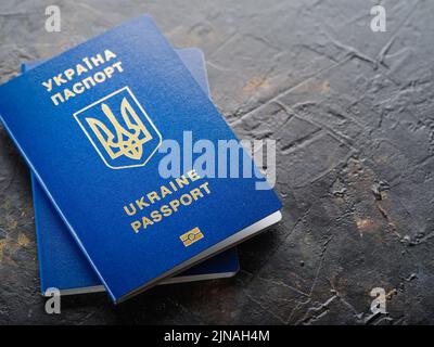 Primer plano. Dos pasaportes biométricos ucranianos azules sobre fondo gris. Identificación personal, viajes al extranjero, turismo, vuelo de la guerra en Ucrania Foto de stock