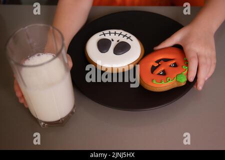 primer plano, la mano de la chica toma calabaza de pan de jengibre de la mesa, halloween fiesta Foto de stock