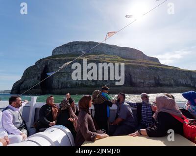 Llandudno, Clwyd, Gales, agosto de 07 2022: La gente disfruta de un viaje en barco con el Gran Orme en el fondo. Foto de stock