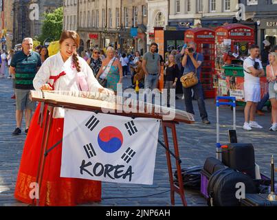 Edimburgo, Escocia, 11 de agosto de 2022 Festival Fringe Músico Coreano en vestido tradicional tocando su instrumento musical de cuerda Foto de stock