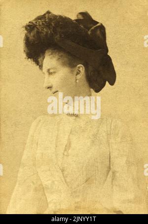Finales del siglo 19th Vintage Fotografía Retrato de mujer joven en perfil posando en estudio fotográfico con sombrero y ropa con estilo de la época de Budapest circa 1889 Foto de stock